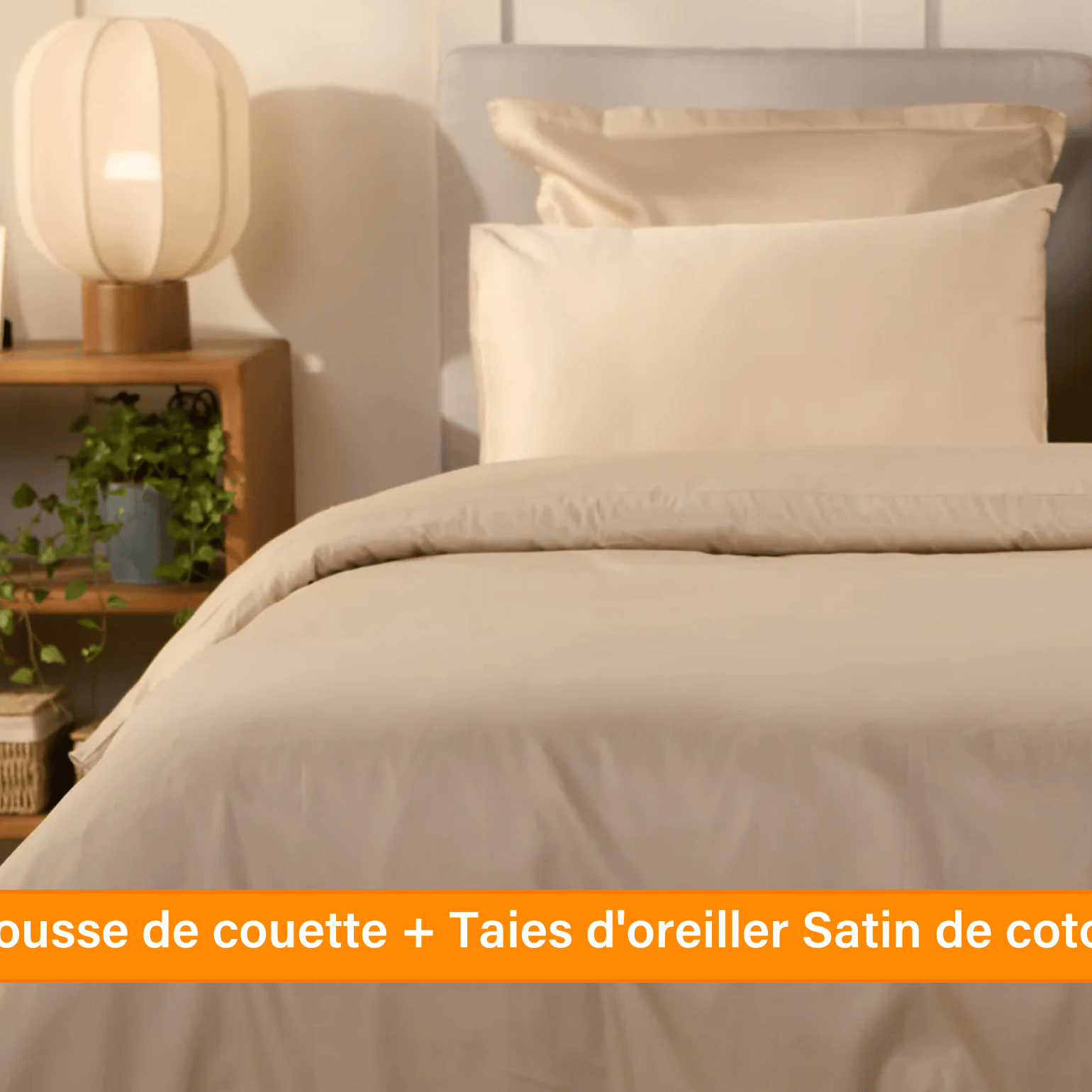 Chambre élégante avec lit soigneusement préparé, habillé d’une parure de lit 100 % satin de coton de couleur blanche ou beige clair. Plusieurs oreillers sont disposés contre un mur à panneaux. De chaque côté du lit, des tables de chevet avec lampe et objets décoratifs. Un banc rose est placé au pied du lit, assorti à un tabouret près de la table de chevet. Le sol en bois clair et les murs neutres créent une ambiance douce et raffinée.