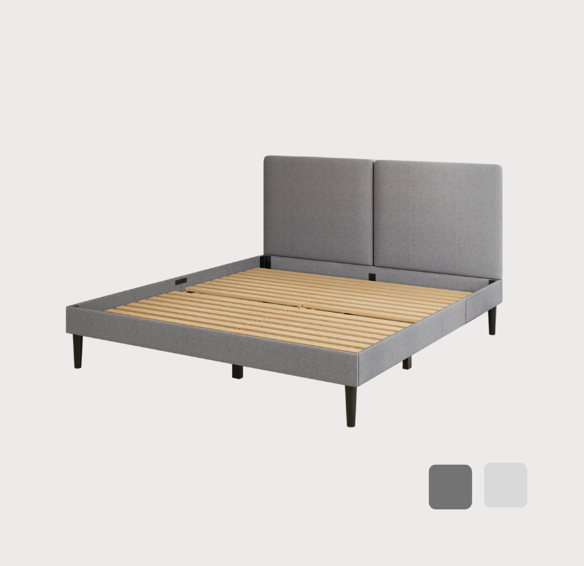 Sommier gris capitonné avec des lattes en bois et des pieds noirs, doté d’une tête de lit moderne à deux panneaux sur fond blanc.