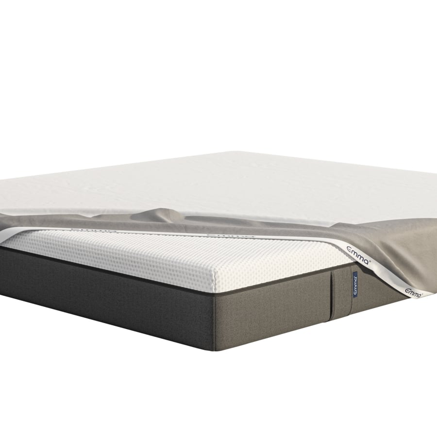 Emma matrasbeschermer in grijze uitvoering met witte rand, gedeeltelijk over wit matras met donkergrijze basis geplaatst; Emma-logo zichtbaar op rand en zijlabel; matras ligt op houten lattenbodem in neutrale setting