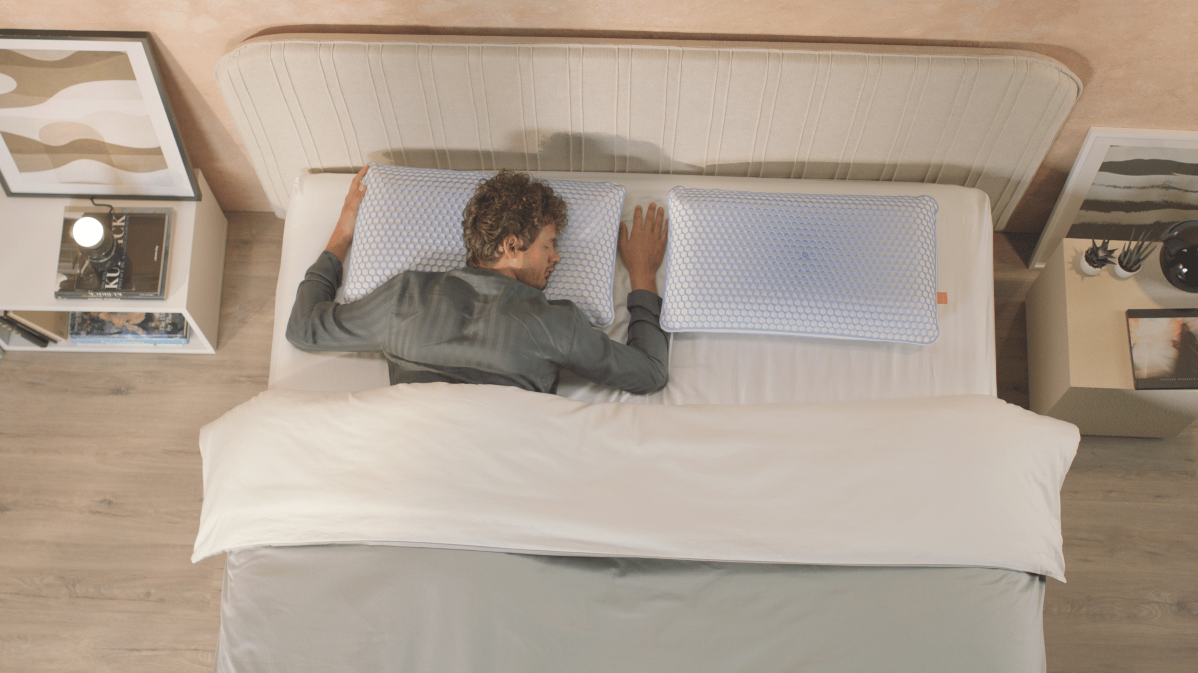 Tweepersoonsbed van bovenaf gezien met twee Emma AirGrid-kussens naast elkaar op een witte matras, in een moderne slaapkamer met houten vloer en nachtkastjes.