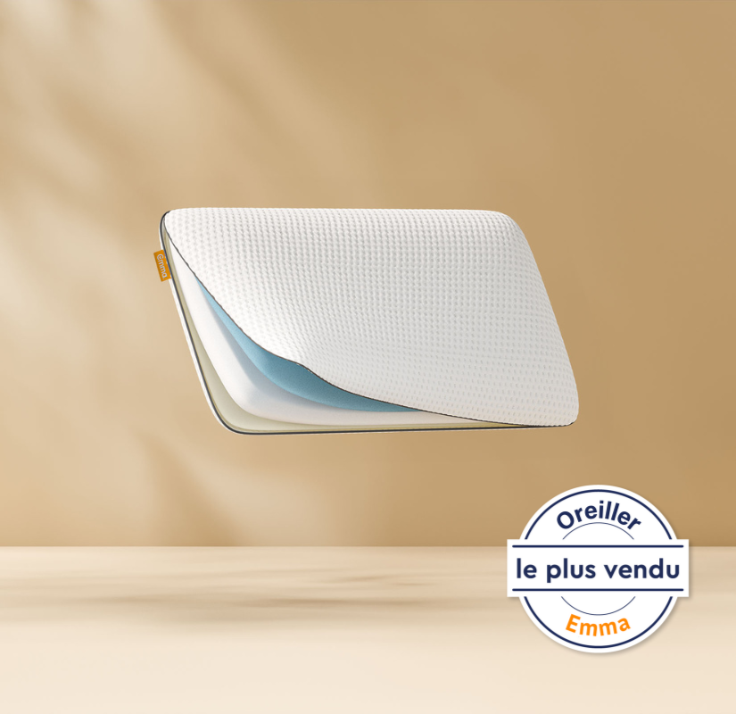 Oreiller flottant montrant ses couches de mousse internes avec un logo Emma. Fond bronze clair.
