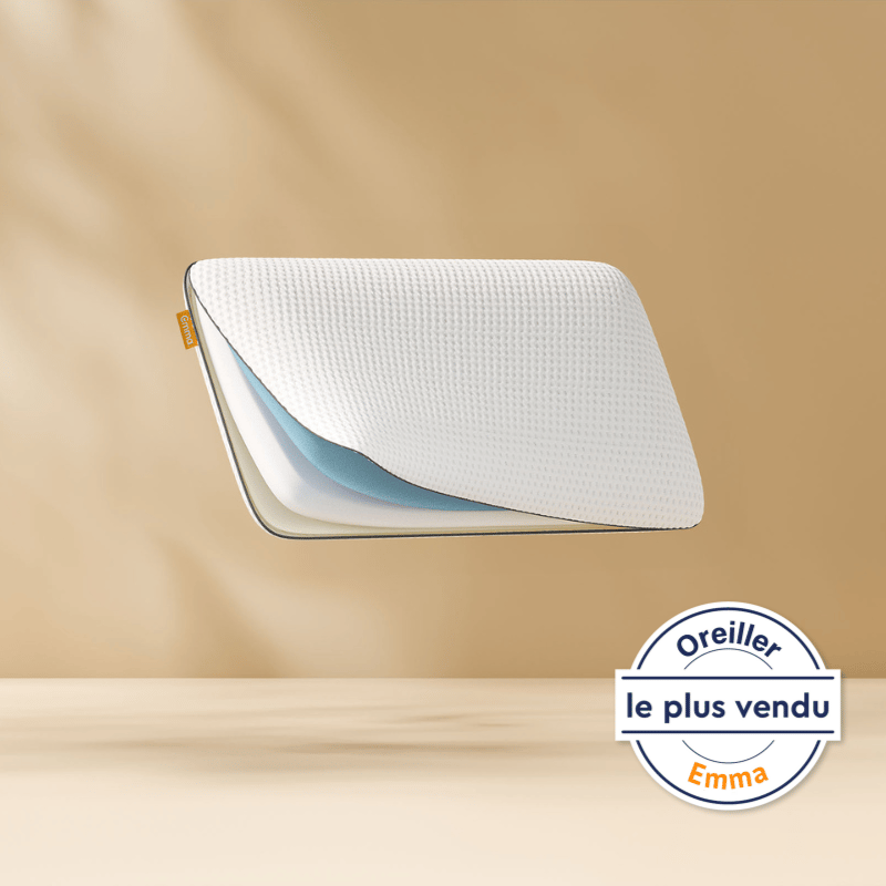 Oreiller flottant montrant ses couches de mousse internes avec un logo Emma. Fond bronze clair.