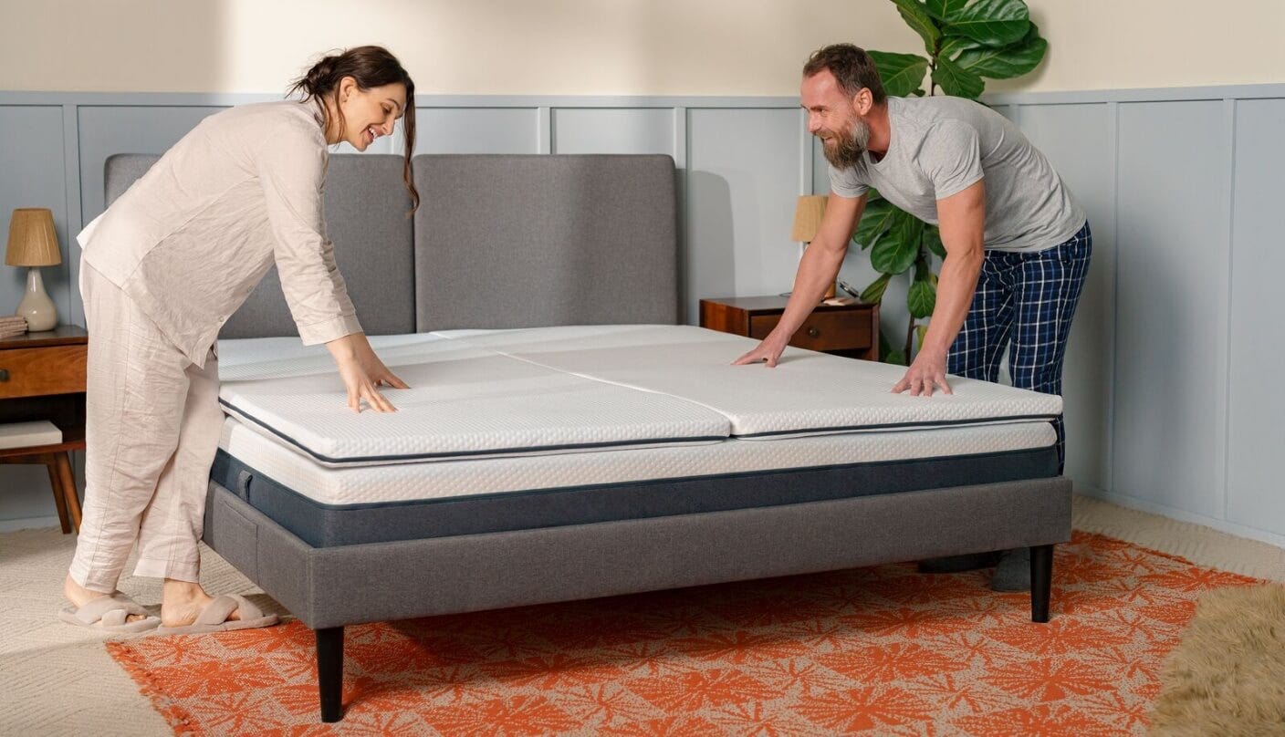 Due persone sistemano un letto con topper.