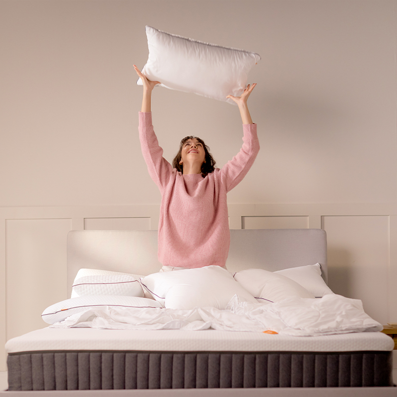 Grey upholstered bed with dark mattress and white pillows.