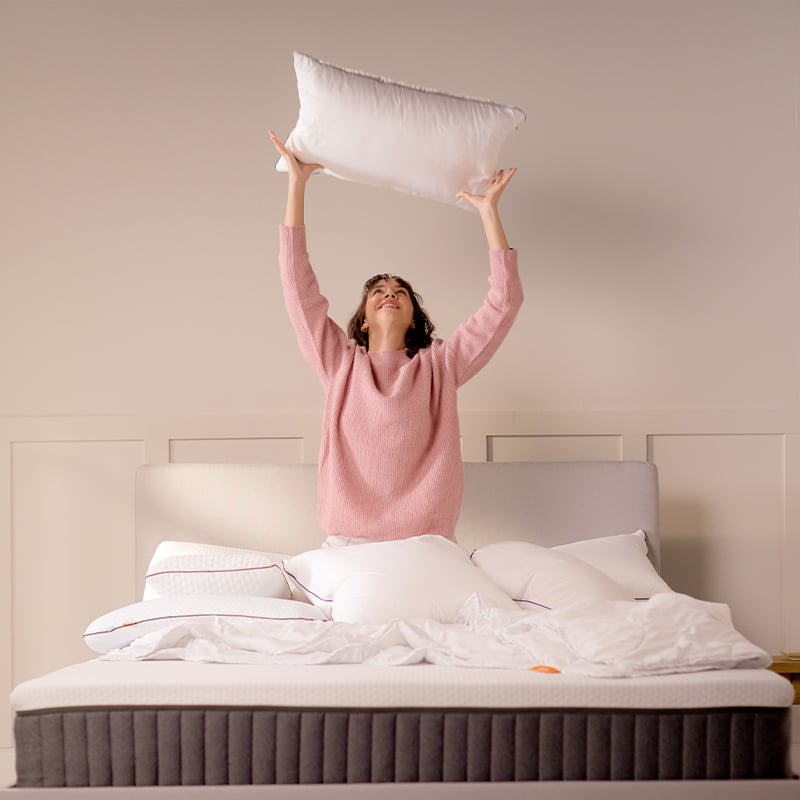 Grey upholstered bed with dark mattress and white pillows.