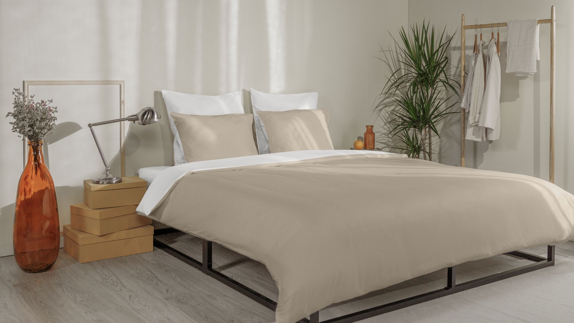 Letto con federe beige e bianche, copripiumino coordinato e testiera in legno a doghe.