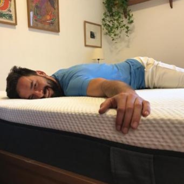 Moço deitado, abraçando o colchão Emma Original. 