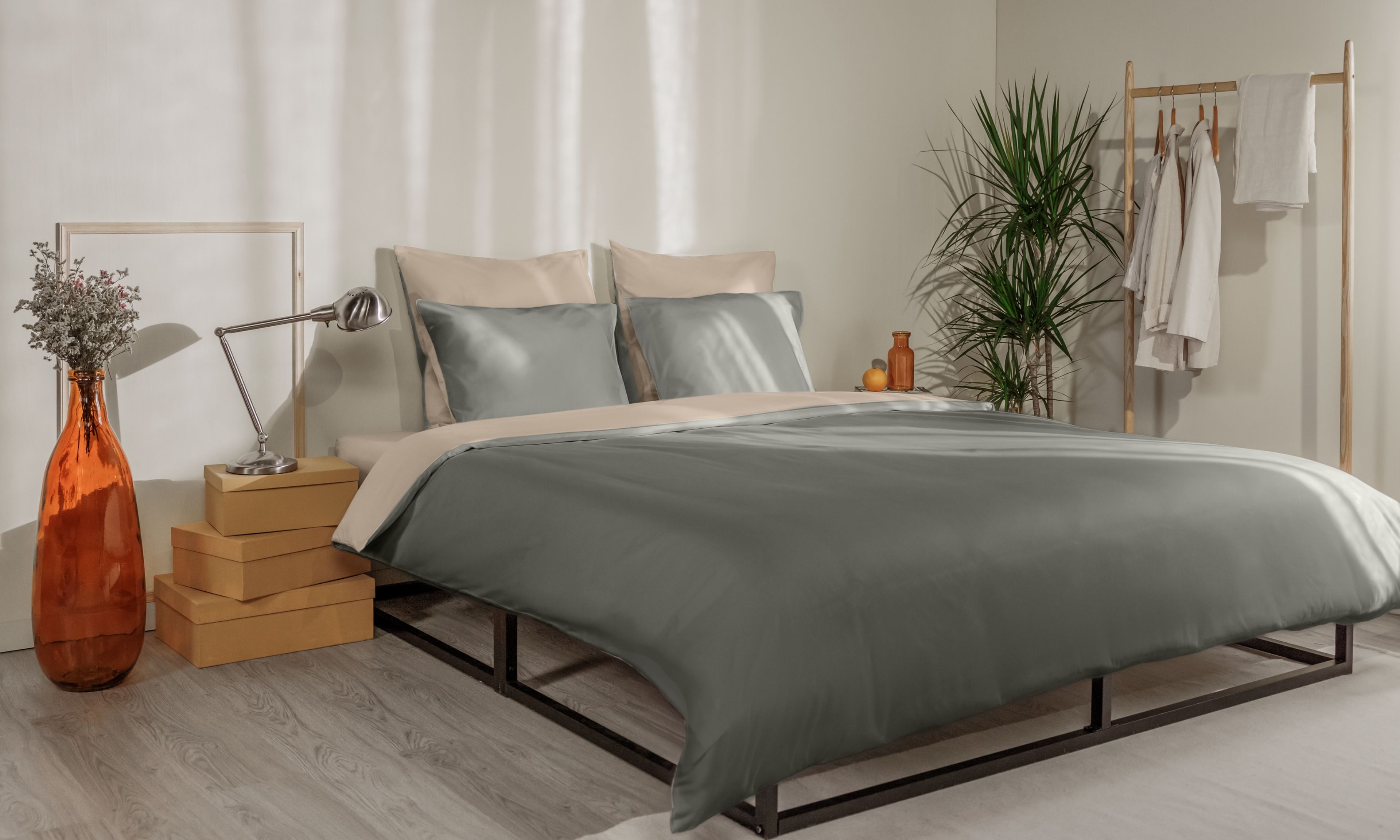 Letto con federe verde scuro e beige, copripiumino coordinato e testiera in legno a doghe.