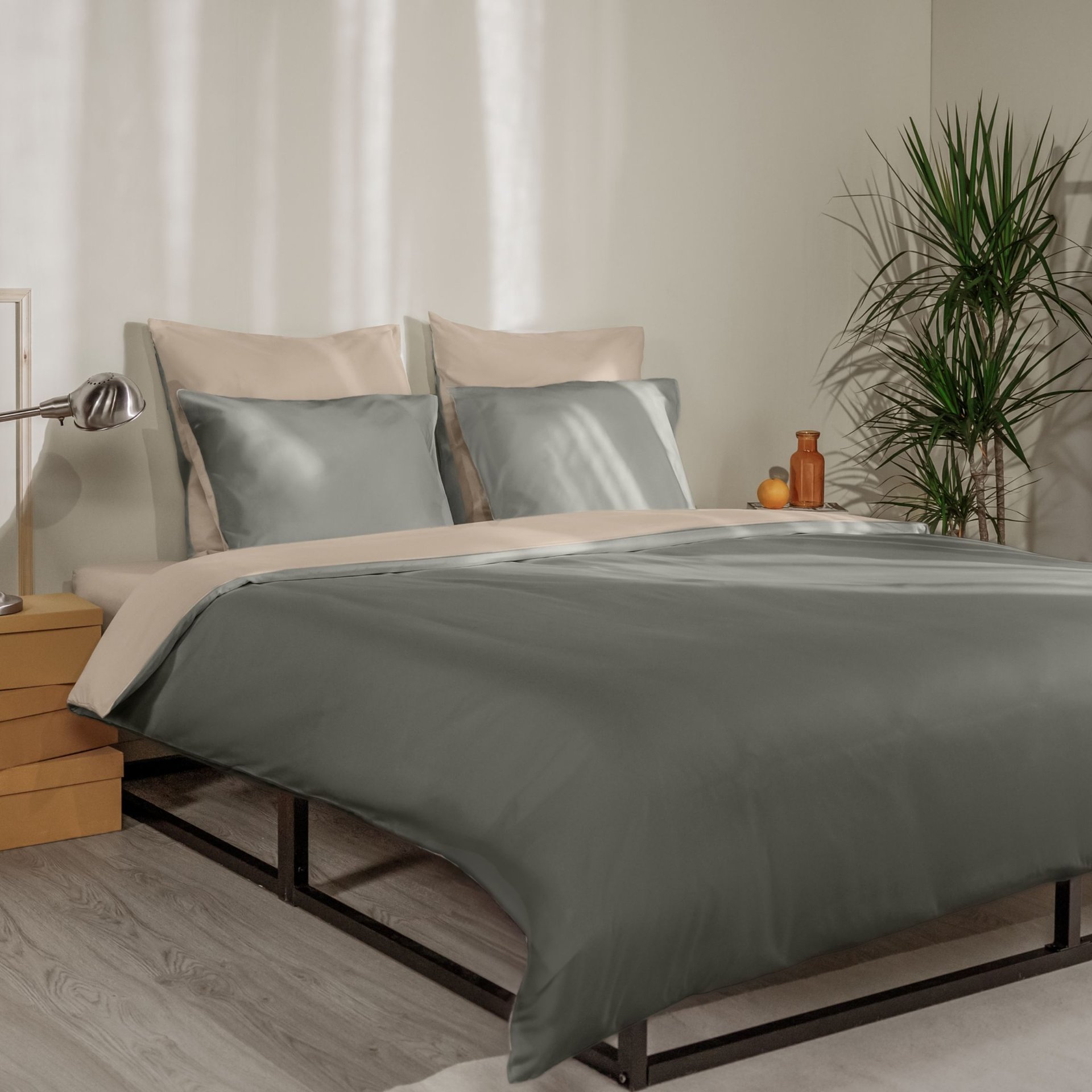 Letto con federe verde scuro e beige, copripiumino coordinato e testiera in legno a doghe.