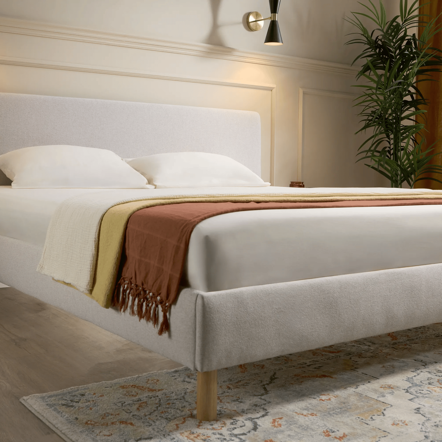 Lichte slaapkamer met grijs bed, wit beddengoed, open boekenkast en grote ramen met daglicht.