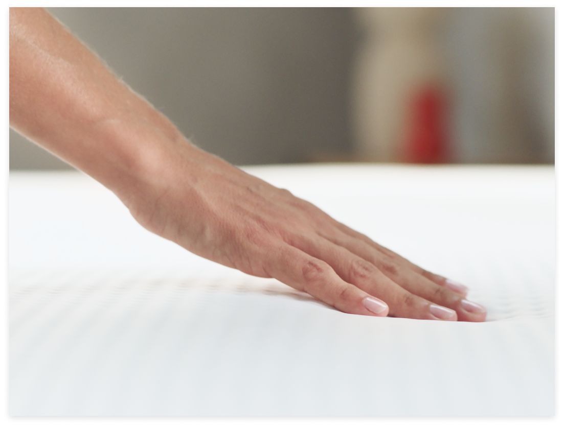 Hand drückt sanft auf eine Matratze