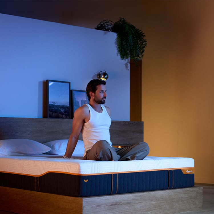 Un hombre sentado sobre un colchón DeepCalm Confort