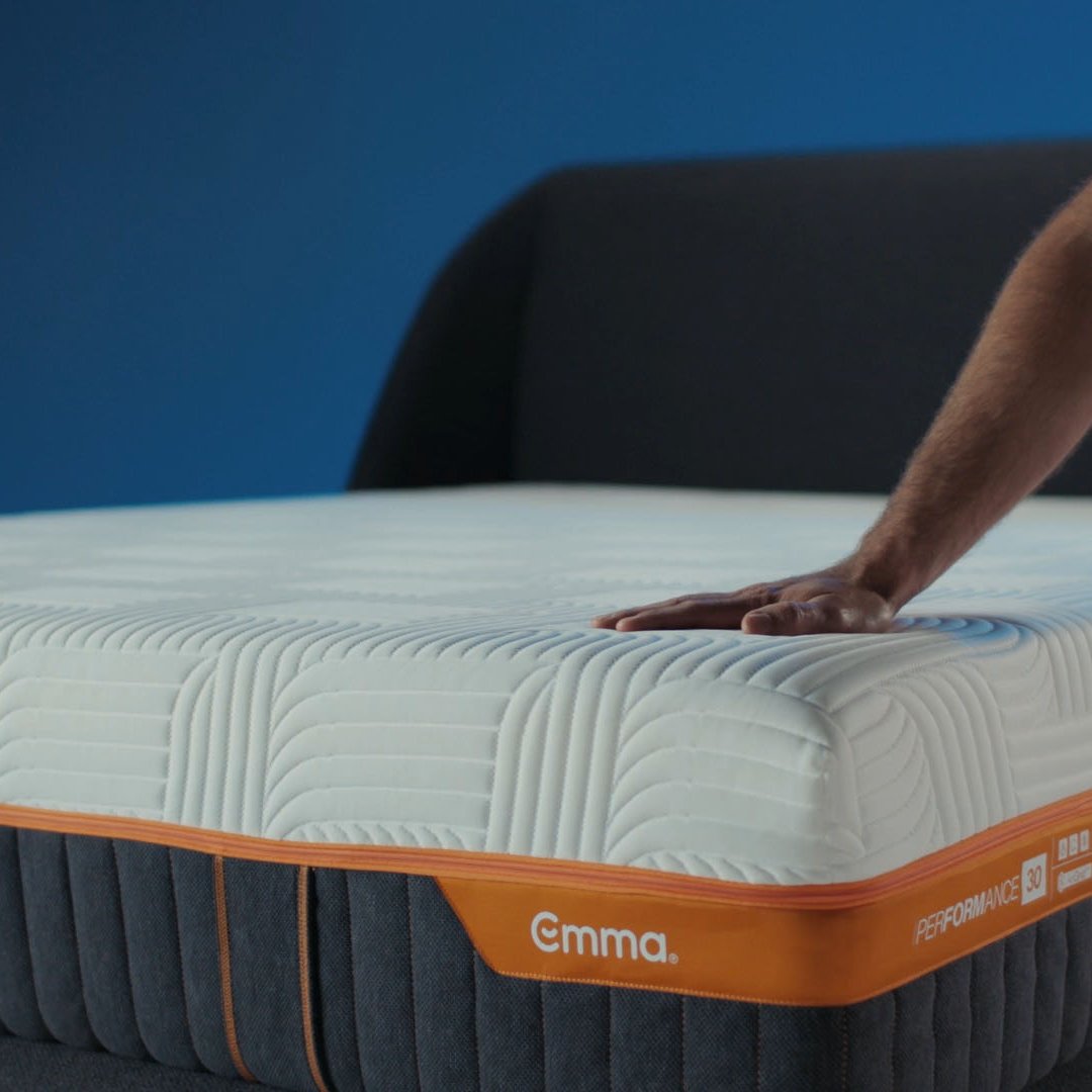 Hand pressing on Emma Performance boxspringbed mattress, demonstrating firmness and responsive support.
