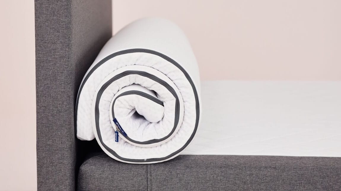 Topper bianco con bordi neri arrotolato su letto grigio