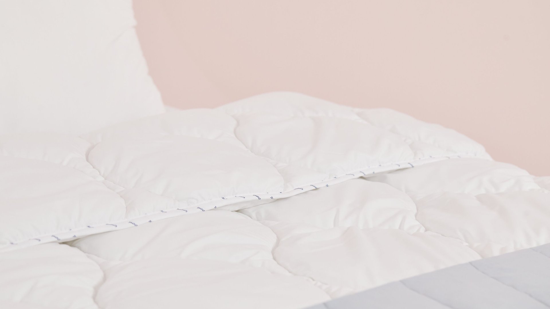edredón blanco con almohada y fondo rosa