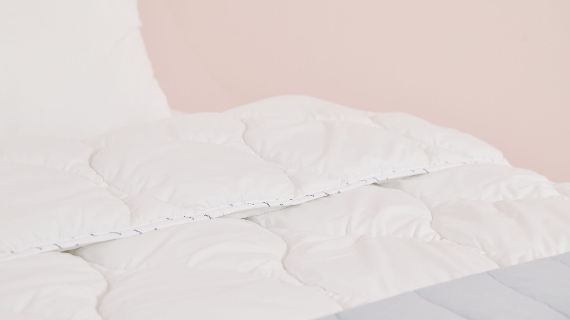 edredón blanco con almohada y fondo rosa