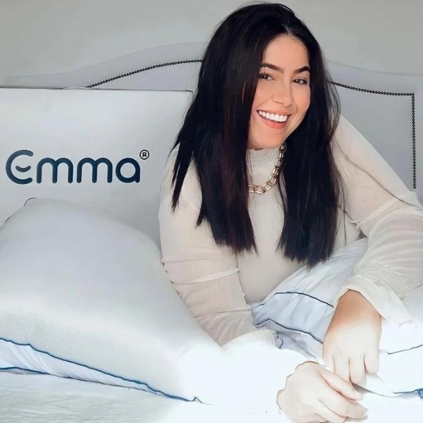 Moça deitada na cama com travesseiro Antiestresse Emma e caixa desse mesmo travesseiro. 