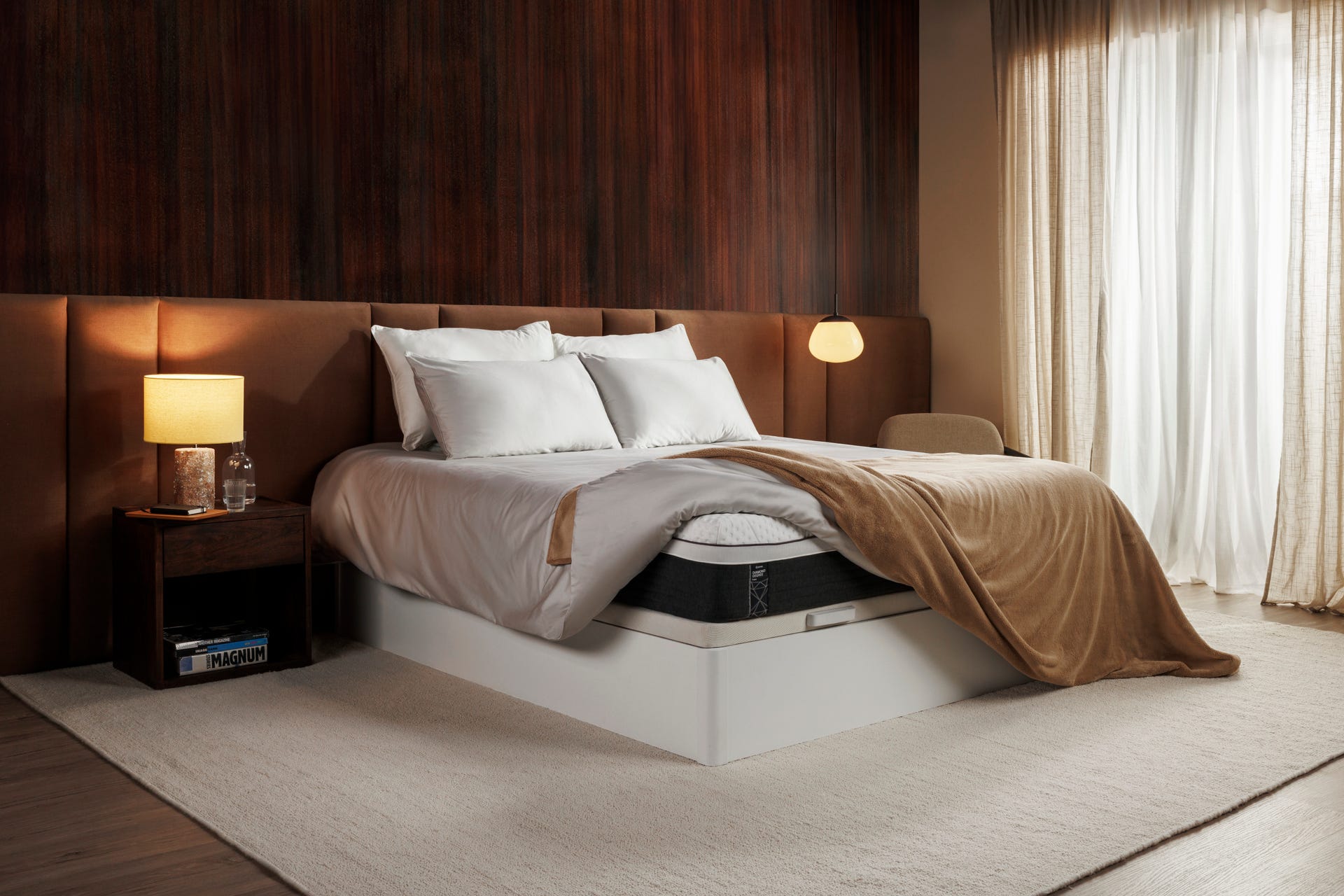 Emma Deluxe Matratze mit weißer Bettwäsche und brauner Decke in elegantem Schlafzimmer.