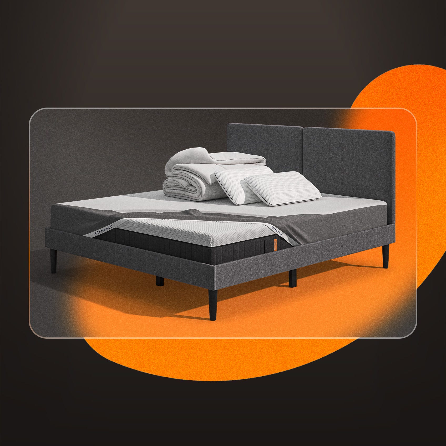 Lit moderne avec tête de lit grise et pieds noirs, recouvert de draps blancs. Deux oreillers blancs et une pile de linge plié sont posés sur le matelas. Arrière-plan beige avec une forme orange abstraite.