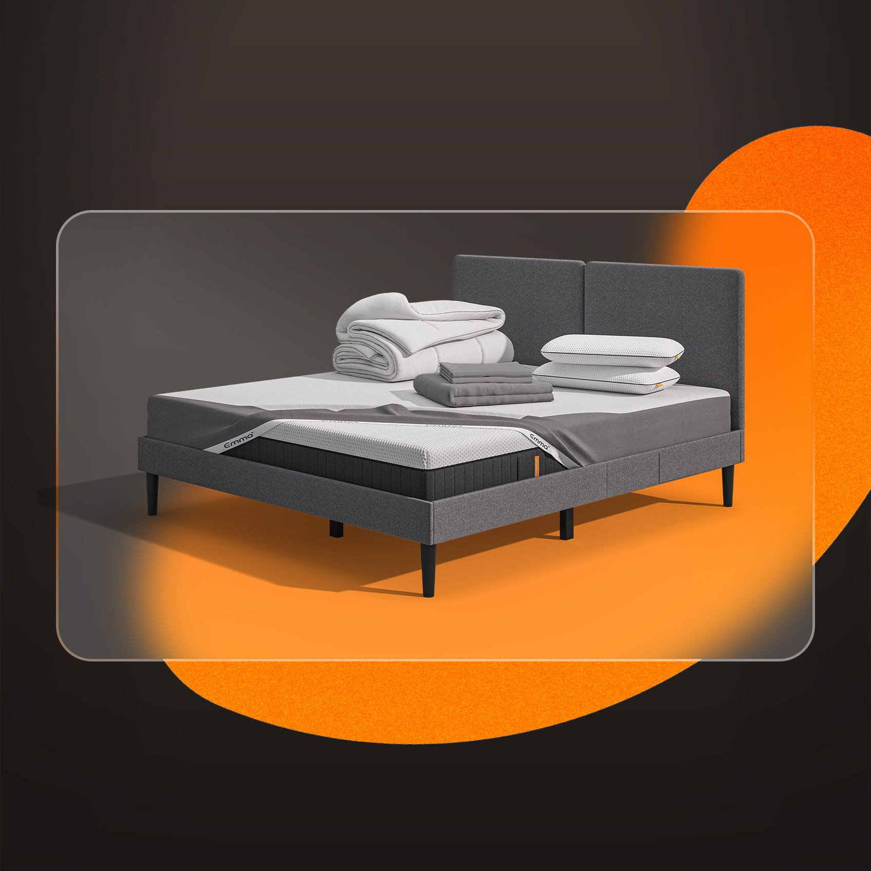 Lit moderne avec tête de lit grise et pieds noirs, recouvert de draps blancs. Deux oreillers blancs et une pile de linge plié sont posés sur le matelas. Arrière-plan beige avec une forme orange abstraite.