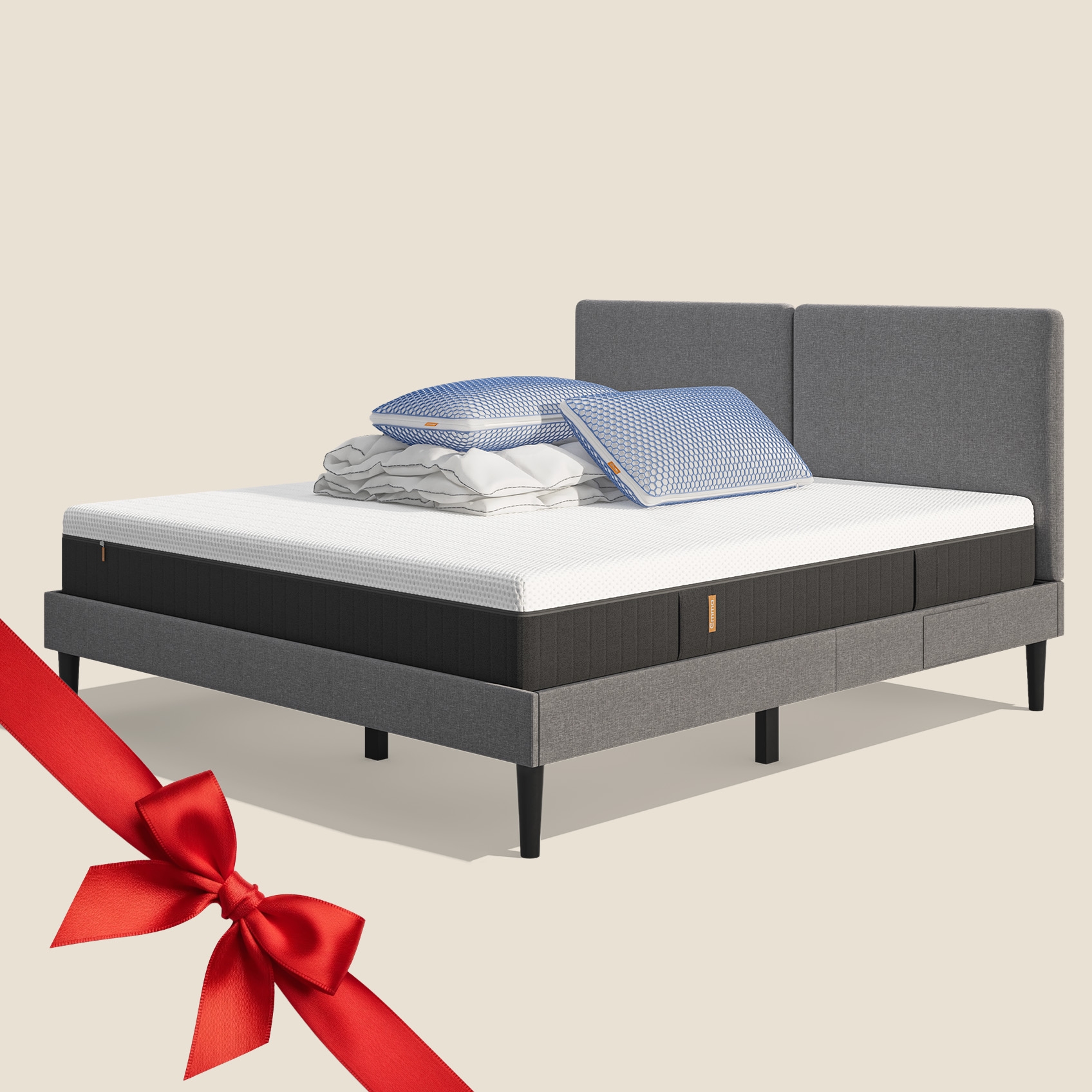 Lit moderne avec tête de lit grise et pieds noirs, recouvert de draps blancs. Deux oreillers blancs et une pile de linge plié sont posés sur le matelas. Arrière-plan beige avec une forme orange abstraite.