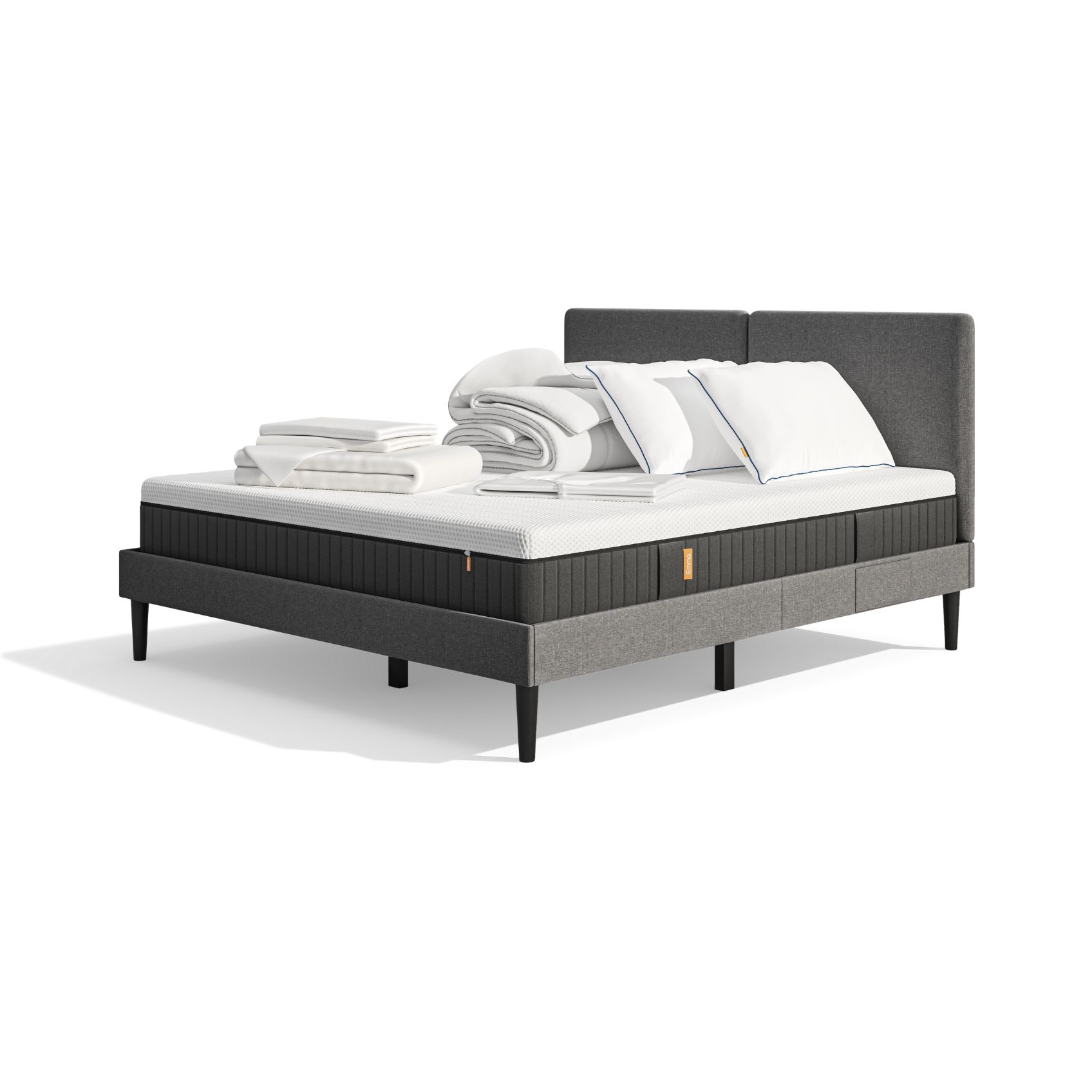 Lit moderne avec tête de lit grise et pieds noirs, recouvert de draps blancs. Deux oreillers blancs et une pile de linge plié sont posés sur le matelas. Arrière-plan beige avec une forme orange abstraite.