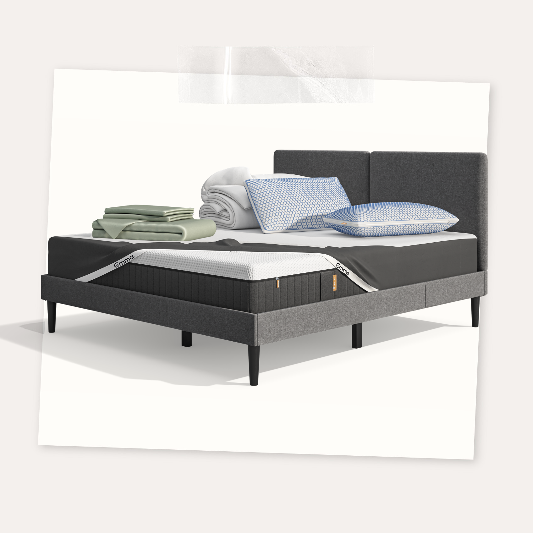 Lit moderne avec tête de lit grise et pieds noirs, recouvert de draps blancs. Deux oreillers blancs et une pile de linge plié sont posés sur le matelas. Arrière-plan beige avec une forme orange abstraite.