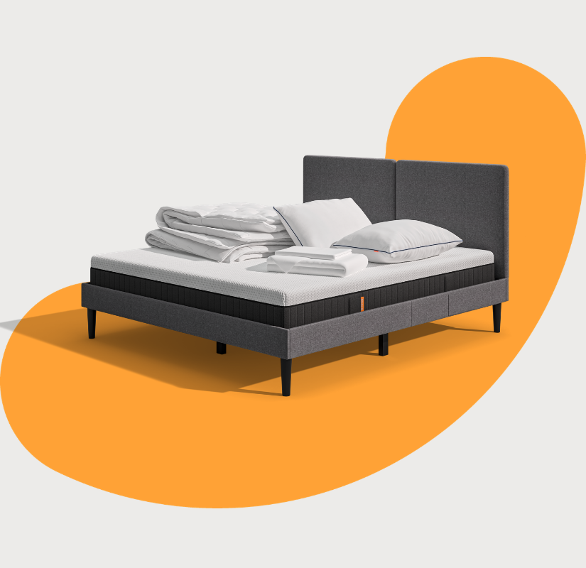 Lit moderne avec tête de lit grise et pieds noirs, recouvert de draps blancs. Deux oreillers blancs et une pile de linge plié sont posés sur le matelas. Arrière-plan beige avec une forme orange abstraite.
