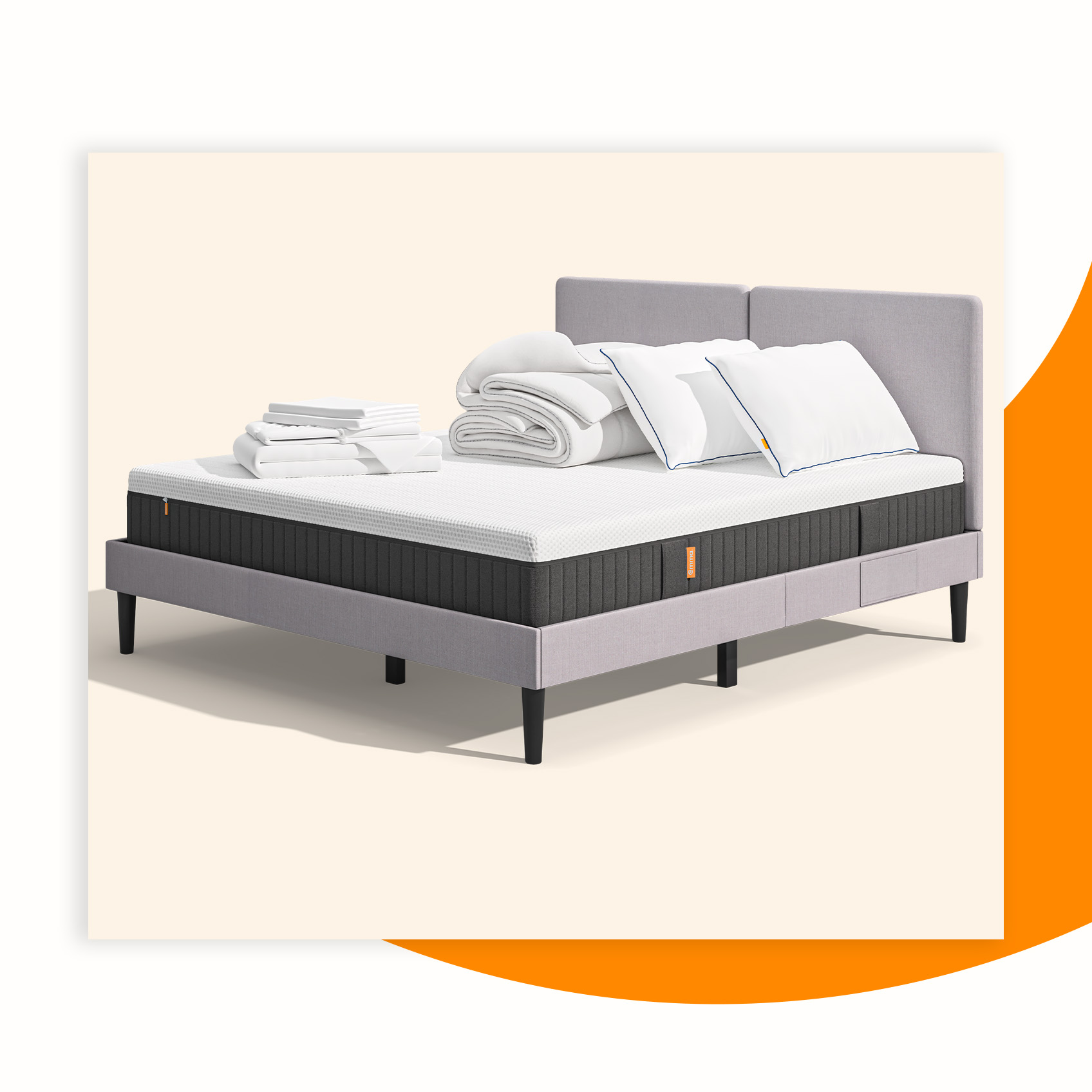 Lit moderne avec tête de lit grise et pieds noirs, recouvert de draps blancs. Deux oreillers blancs et une pile de linge plié sont posés sur le matelas. Arrière-plan beige avec une forme orange abstraite.