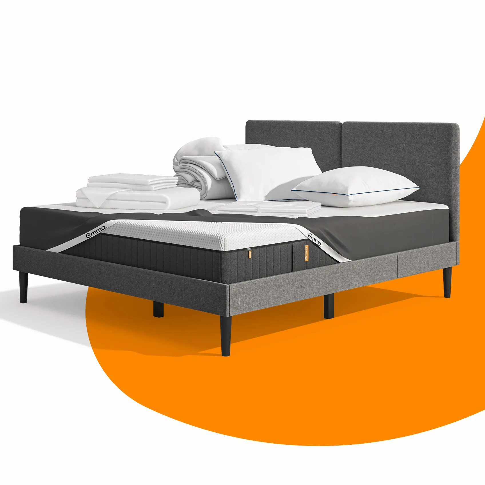 Lit moderne avec tête de lit grise et pieds noirs, recouvert de draps blancs. Deux oreillers blancs et une pile de linge plié sont posés sur le matelas. Arrière-plan beige avec une forme orange abstraite.