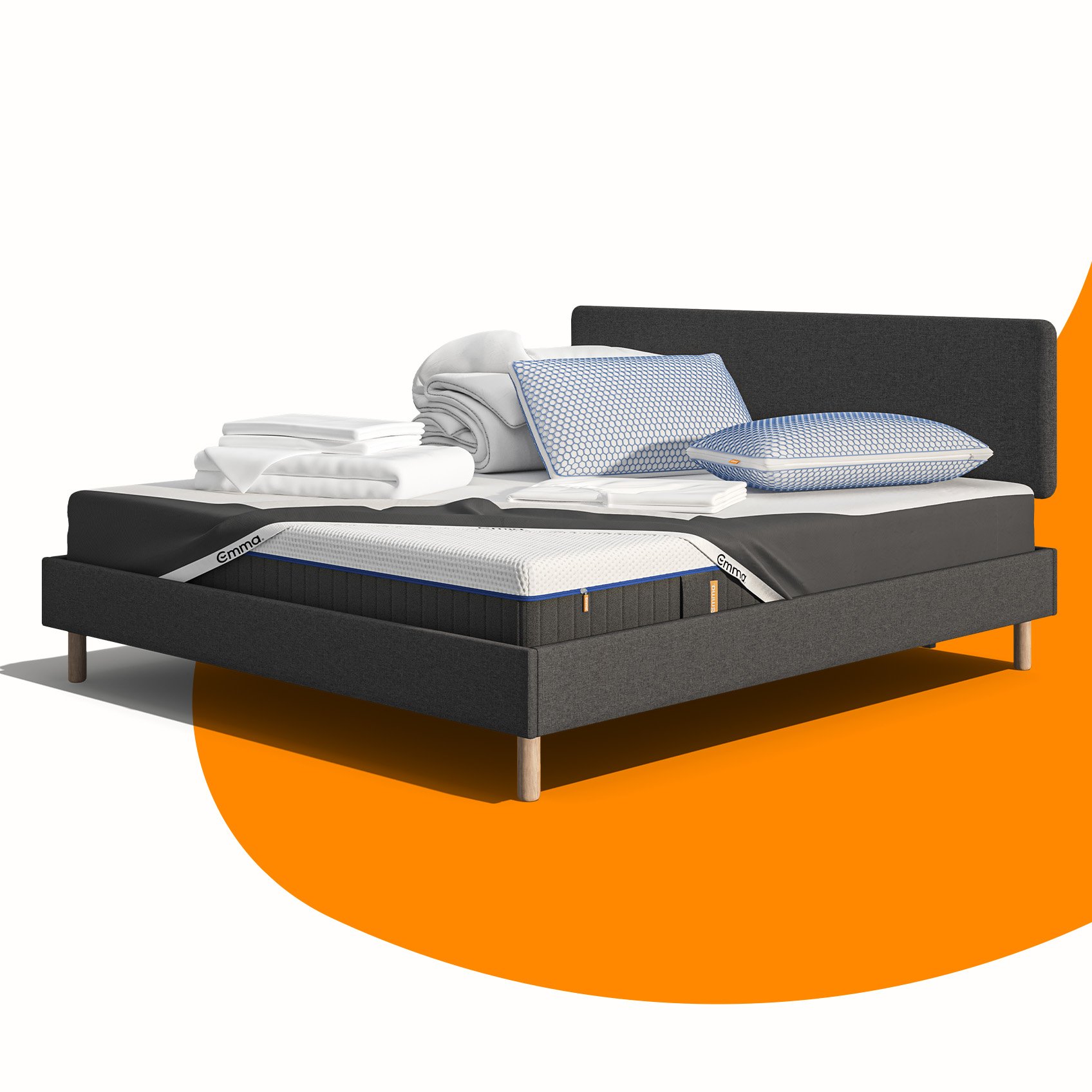 Lit moderne avec tête de lit grise et pieds noirs, recouvert de draps blancs. Deux oreillers blancs et une pile de linge plié sont posés sur le matelas. Arrière-plan beige avec une forme orange abstraite.