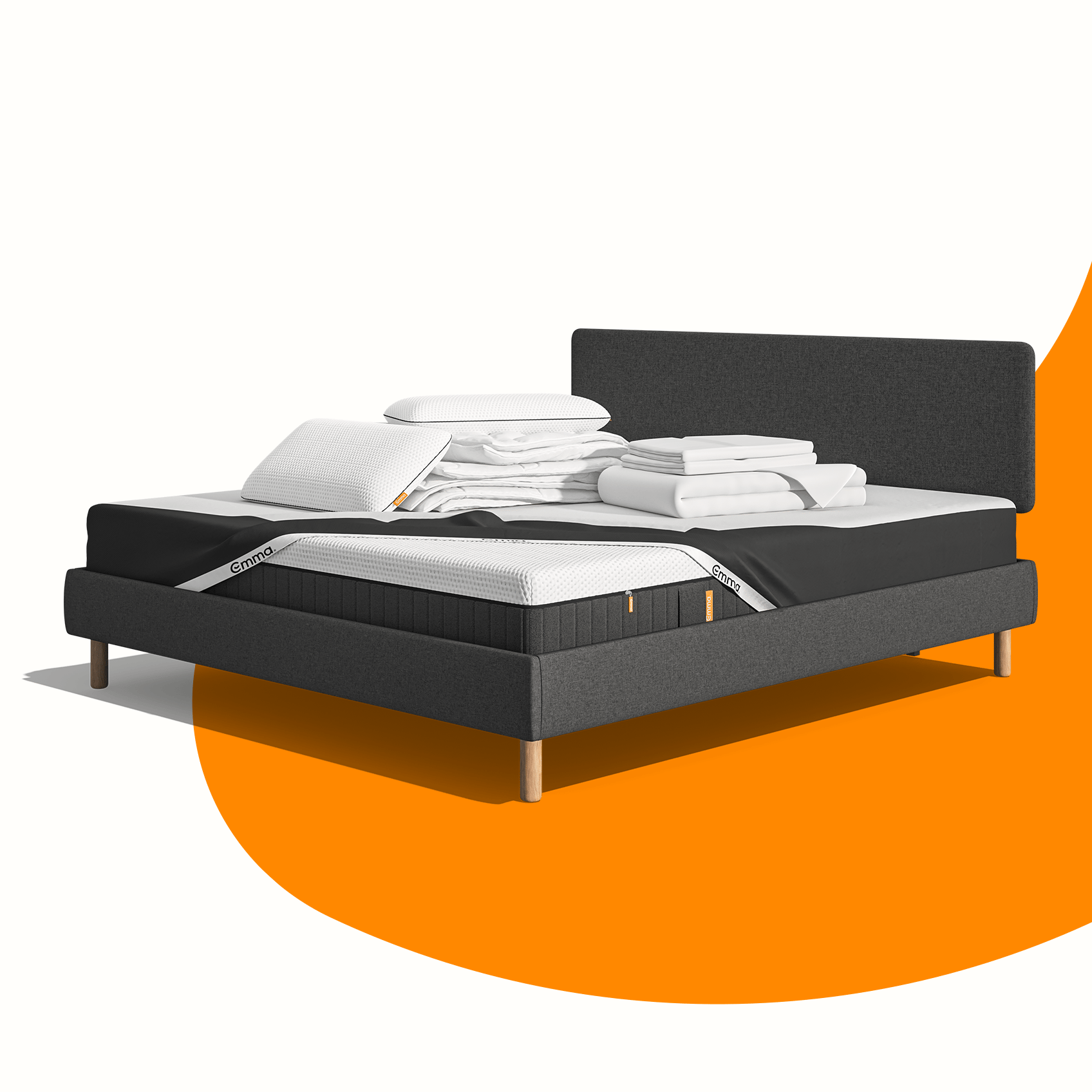 Lit moderne avec tête de lit grise et pieds noirs, recouvert de draps blancs. Deux oreillers blancs et une pile de linge plié sont posés sur le matelas. Arrière-plan beige avec une forme orange abstraite.