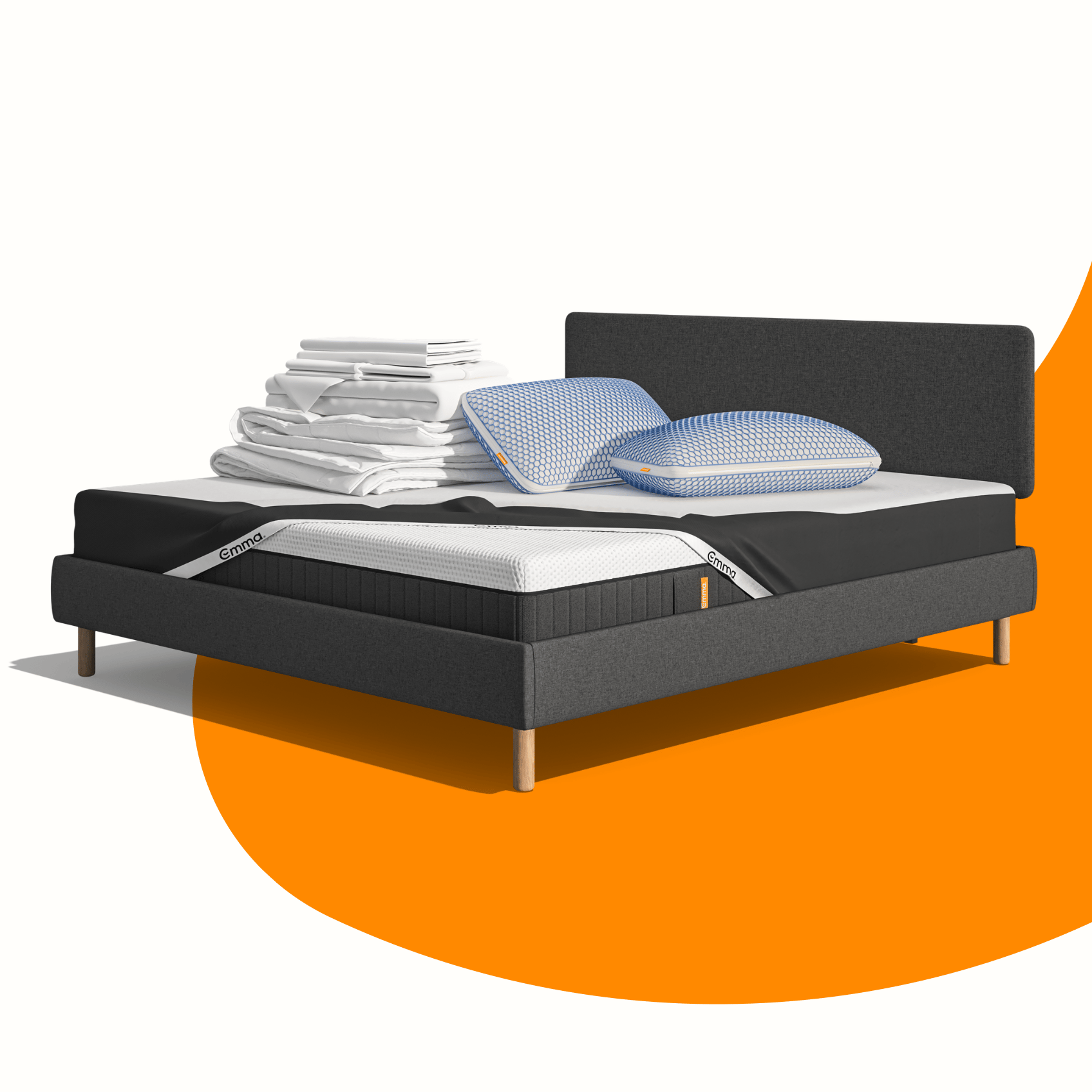 Lit moderne avec tête de lit grise et pieds noirs, recouvert de draps blancs. Deux oreillers blancs et une pile de linge plié sont posés sur le matelas. Arrière-plan beige avec une forme orange abstraite.