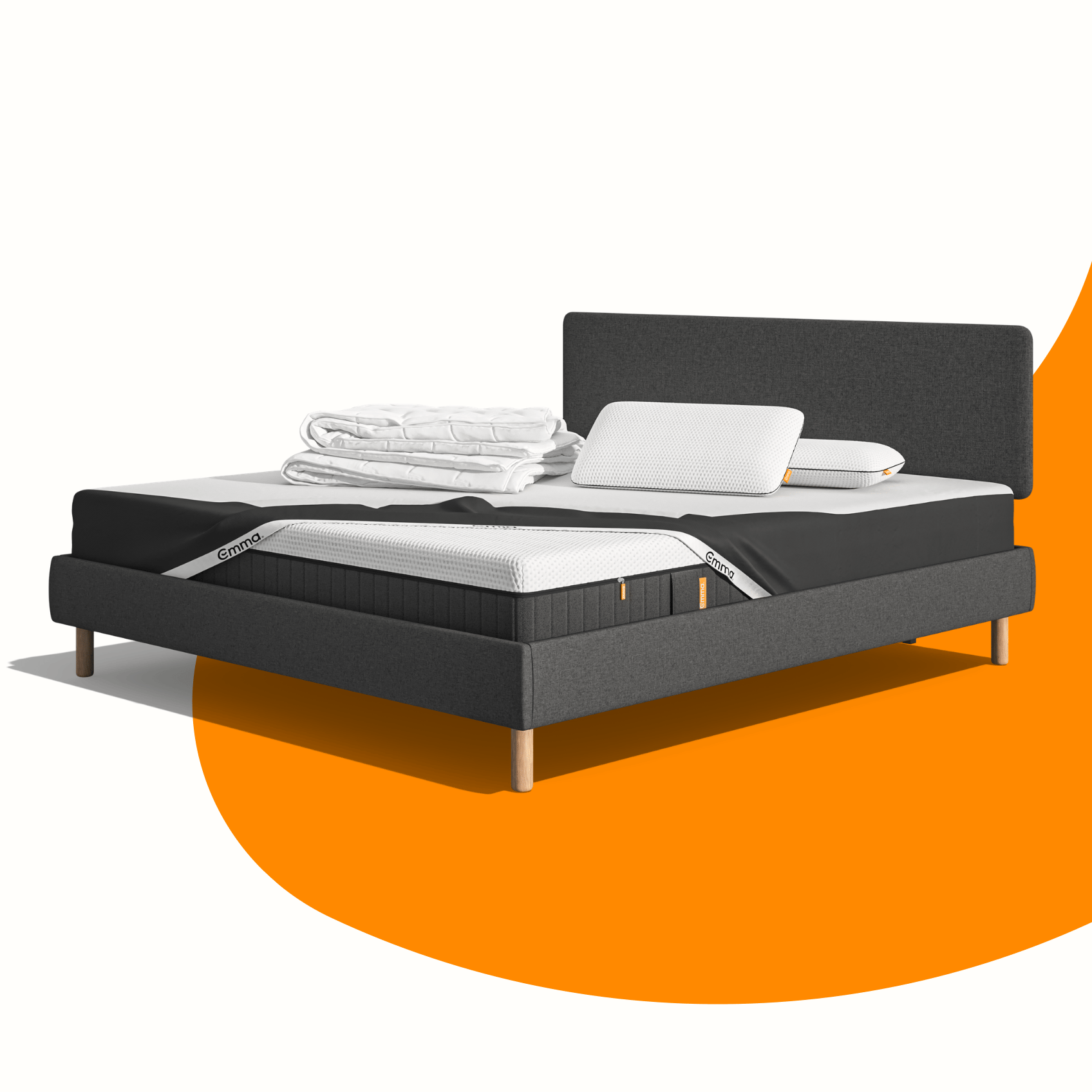 Lit moderne avec tête de lit grise et pieds noirs, recouvert de draps blancs. Deux oreillers blancs et une pile de linge plié sont posés sur le matelas. Arrière-plan beige avec une forme orange abstraite.