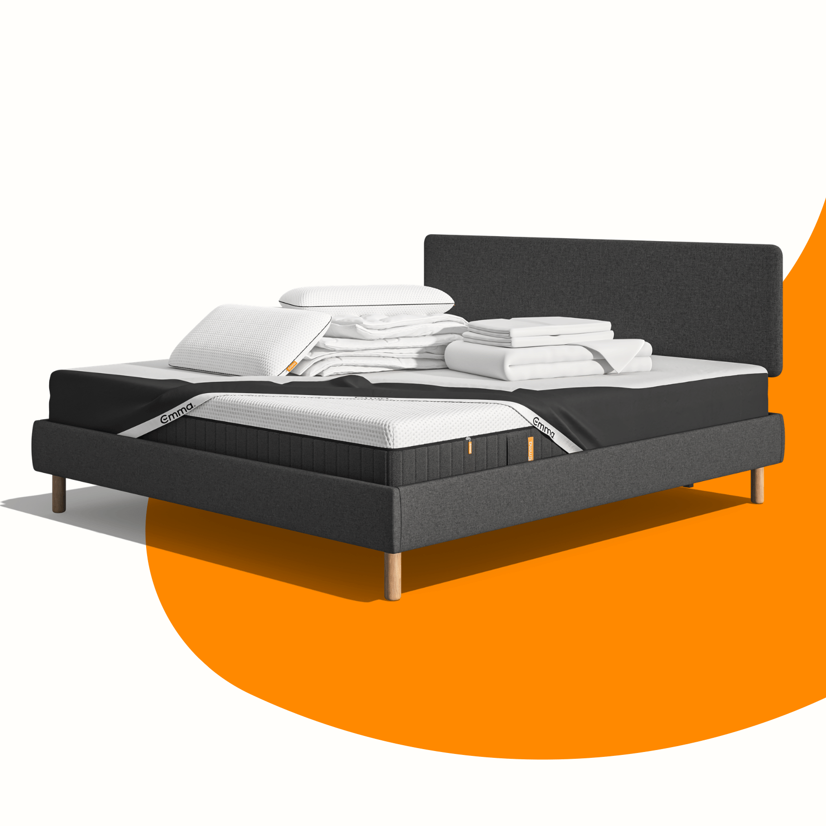 Lit moderne avec tête de lit grise et pieds noirs, recouvert de draps blancs. Deux oreillers blancs et une pile de linge plié sont posés sur le matelas. Arrière-plan beige avec une forme orange abstraite.