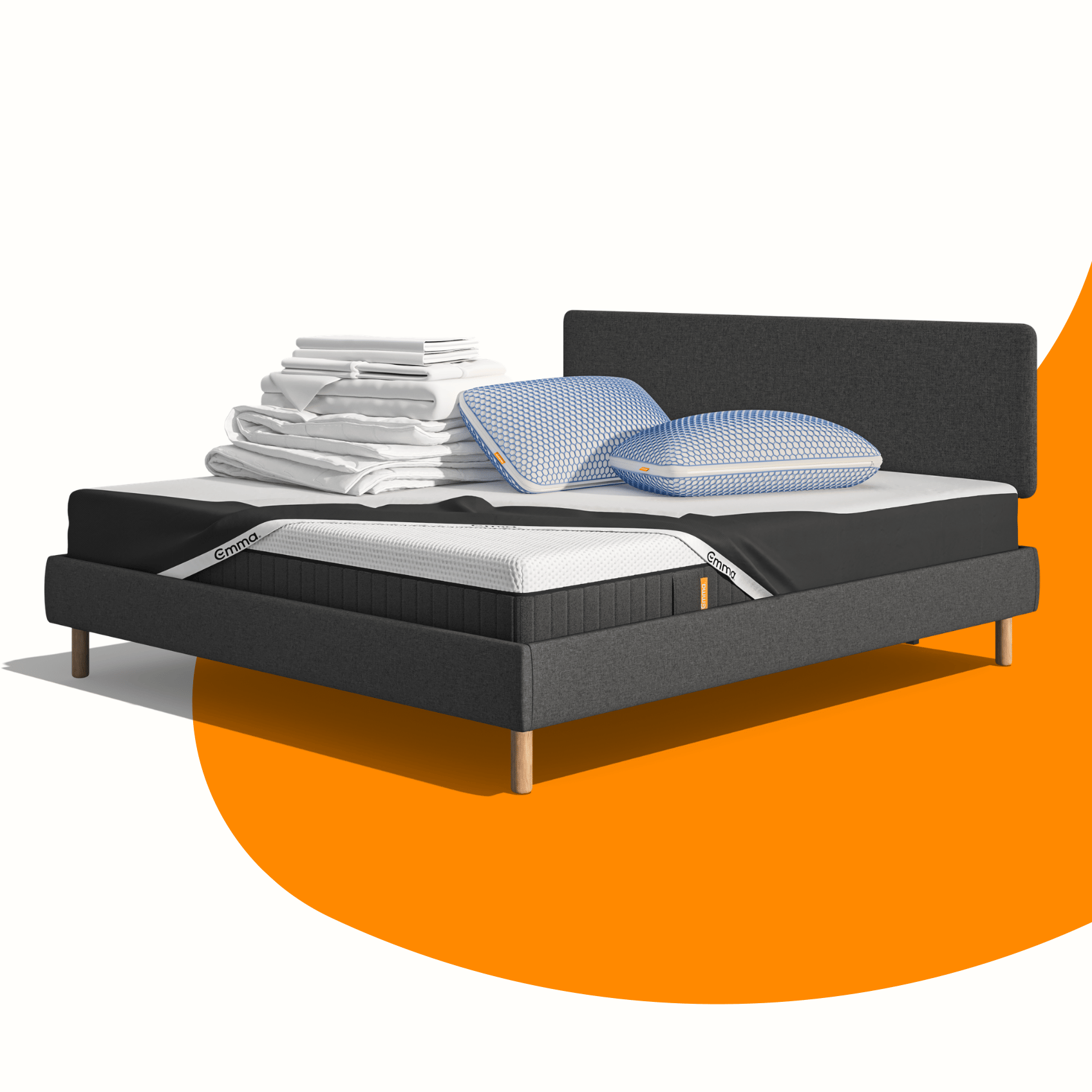 Lit moderne avec tête de lit grise et pieds noirs, recouvert de draps blancs. Deux oreillers blancs et une pile de linge plié sont posés sur le matelas. Arrière-plan beige avec une forme orange abstraite.