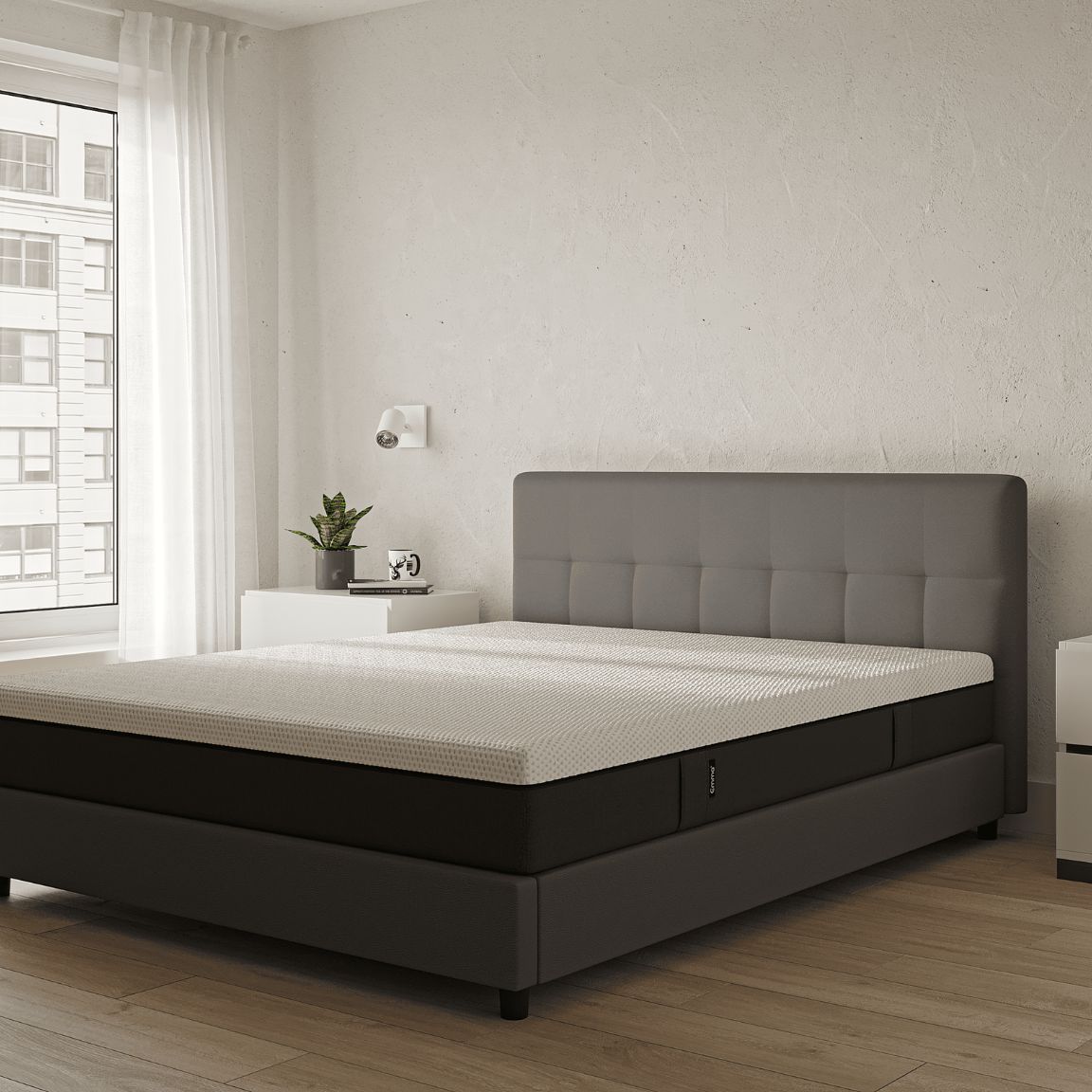 Camera moderna con letto imbottito grigio, comodini bianchi e ampie finestre con tende bianche.