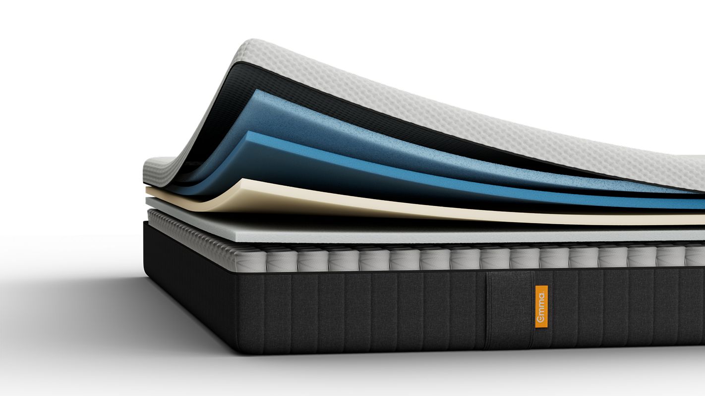 Lit tapissé gris avec matelas blanc, dans une chambre.