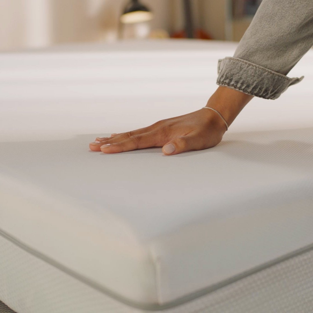 Person pressing the mattress surface to show its feel.