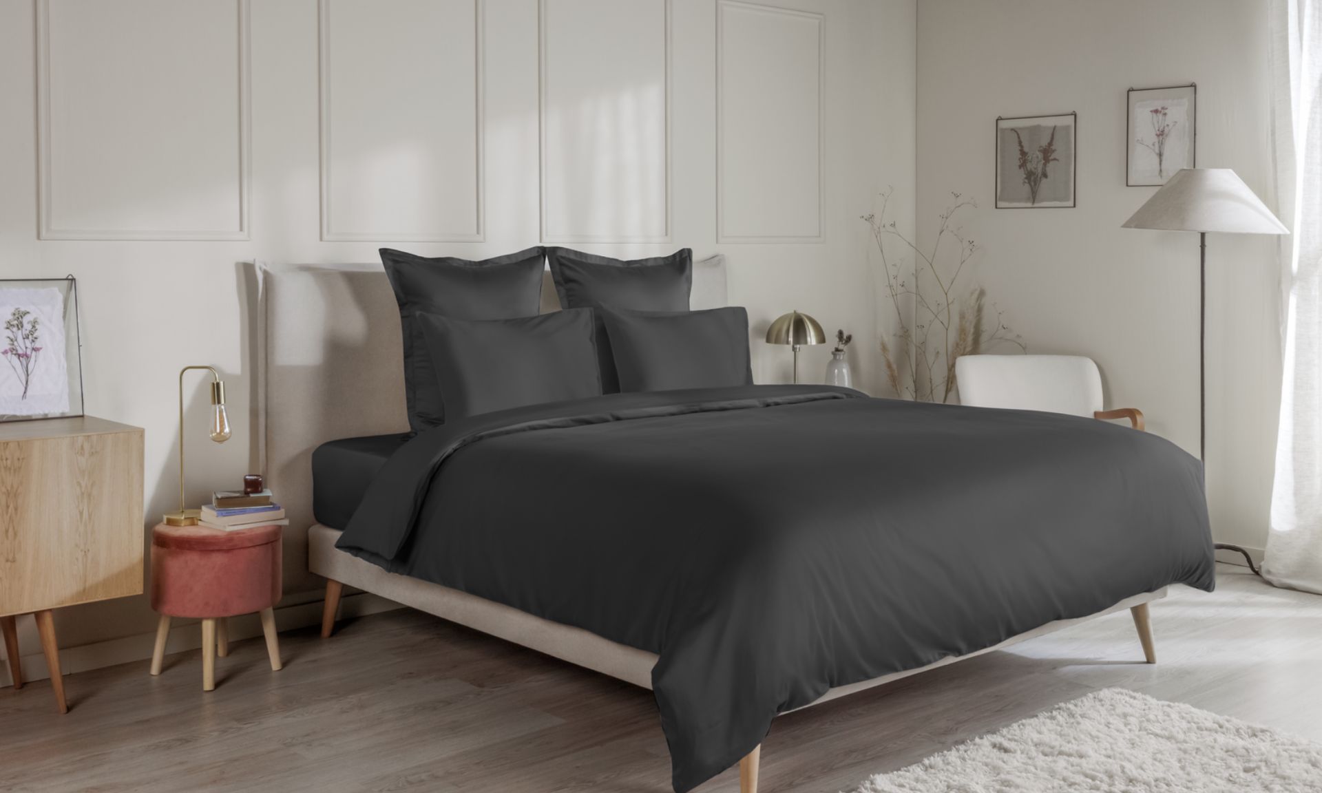 Letto con federe grigio scuro, copripiumino coordinato e testiera in legno a doghe.