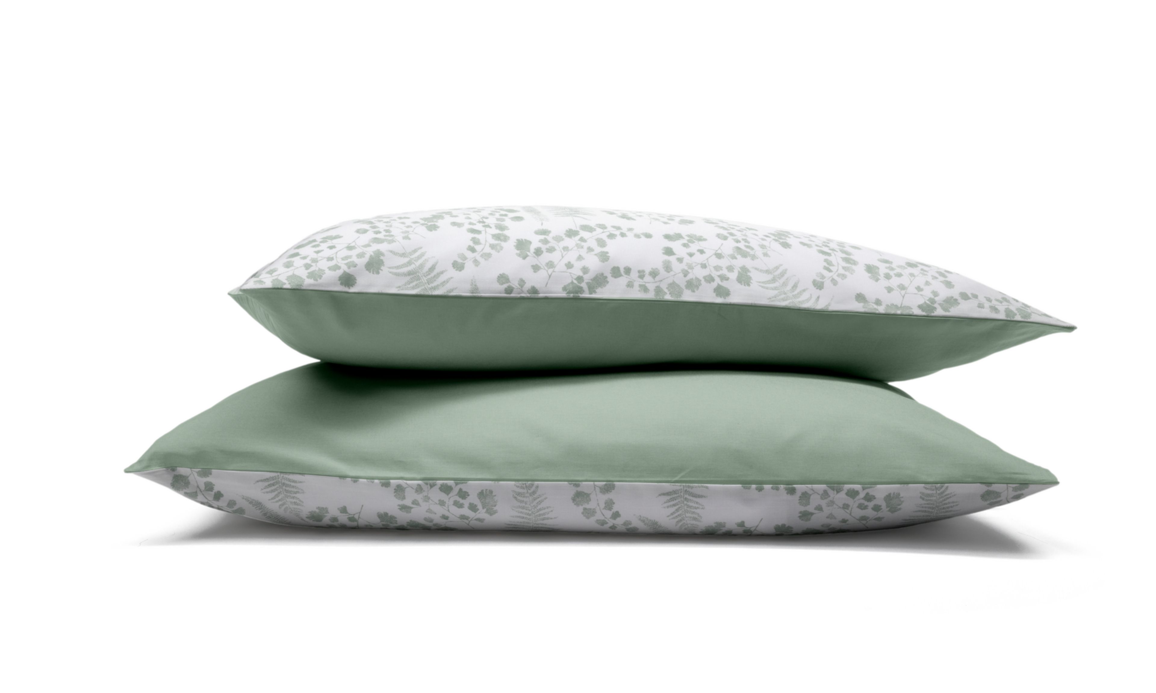 Due federe con motivo floreale verde e bianco impilate su sfondo bianco.