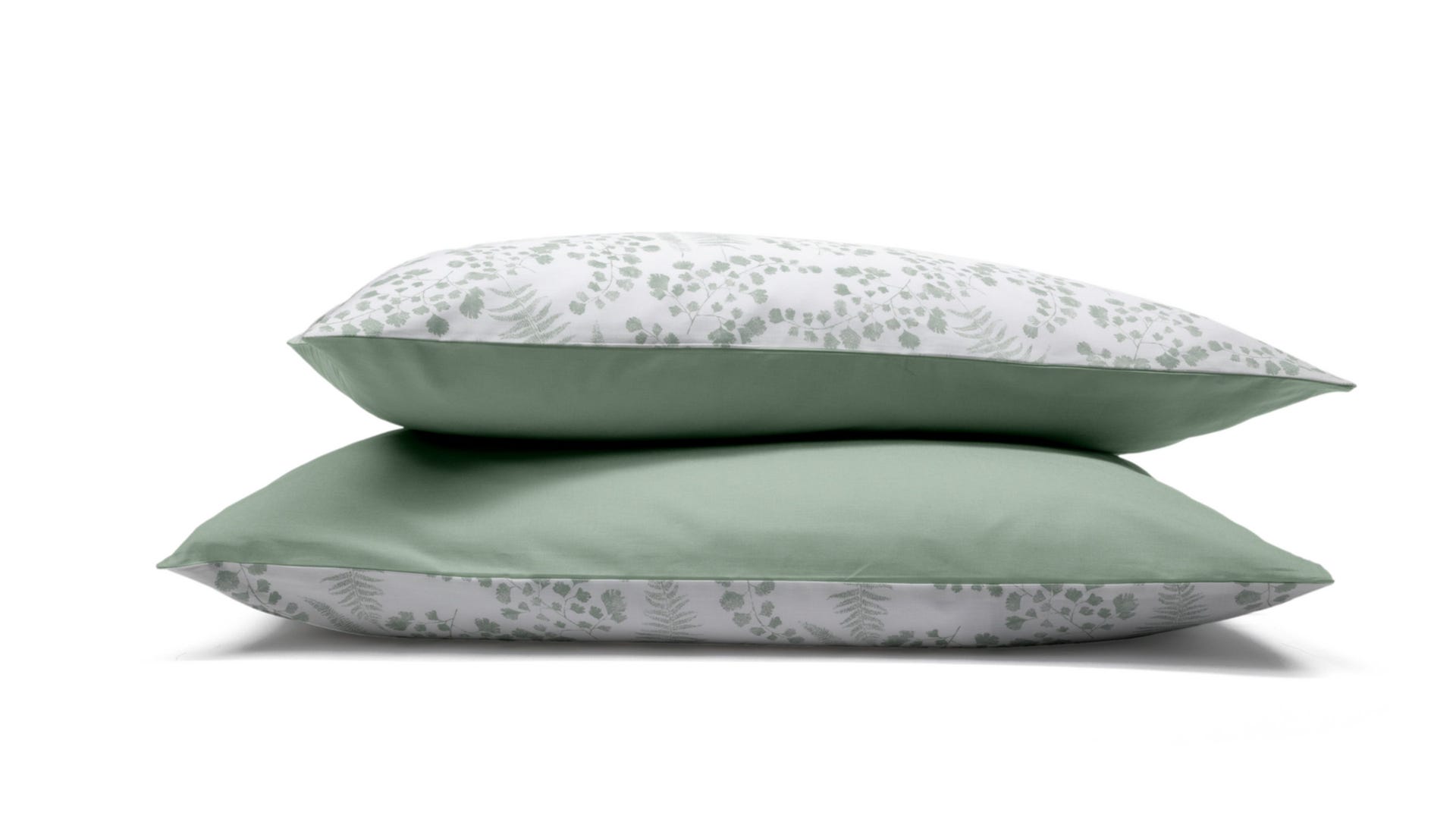 Due federe con motivo floreale verde e bianco impilate su sfondo bianco.