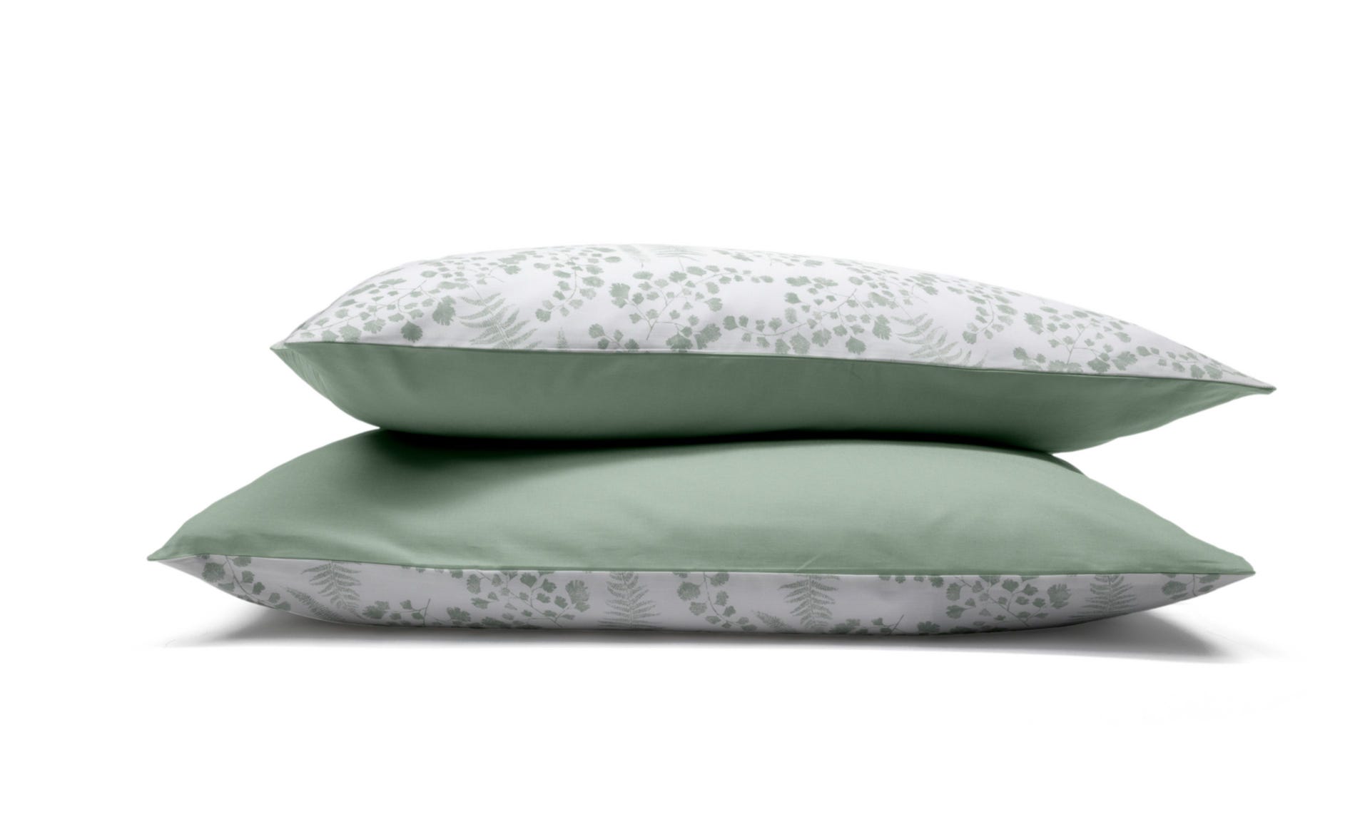 Due federe con motivo floreale verde e bianco impilate su sfondo bianco.