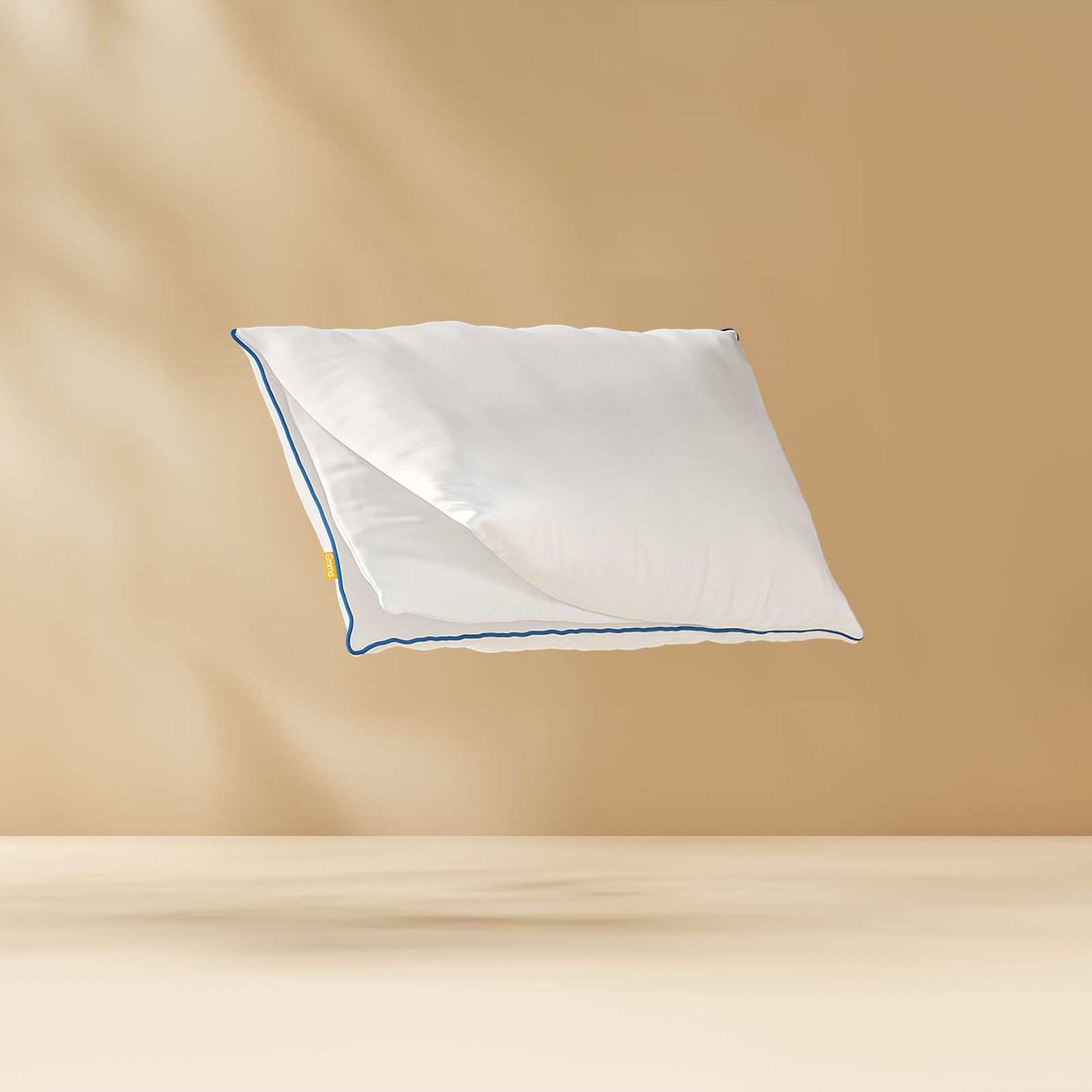 Oreiller flottant montrant ses couches de mousse internes avec un logo Emma. Fond bronze clair.