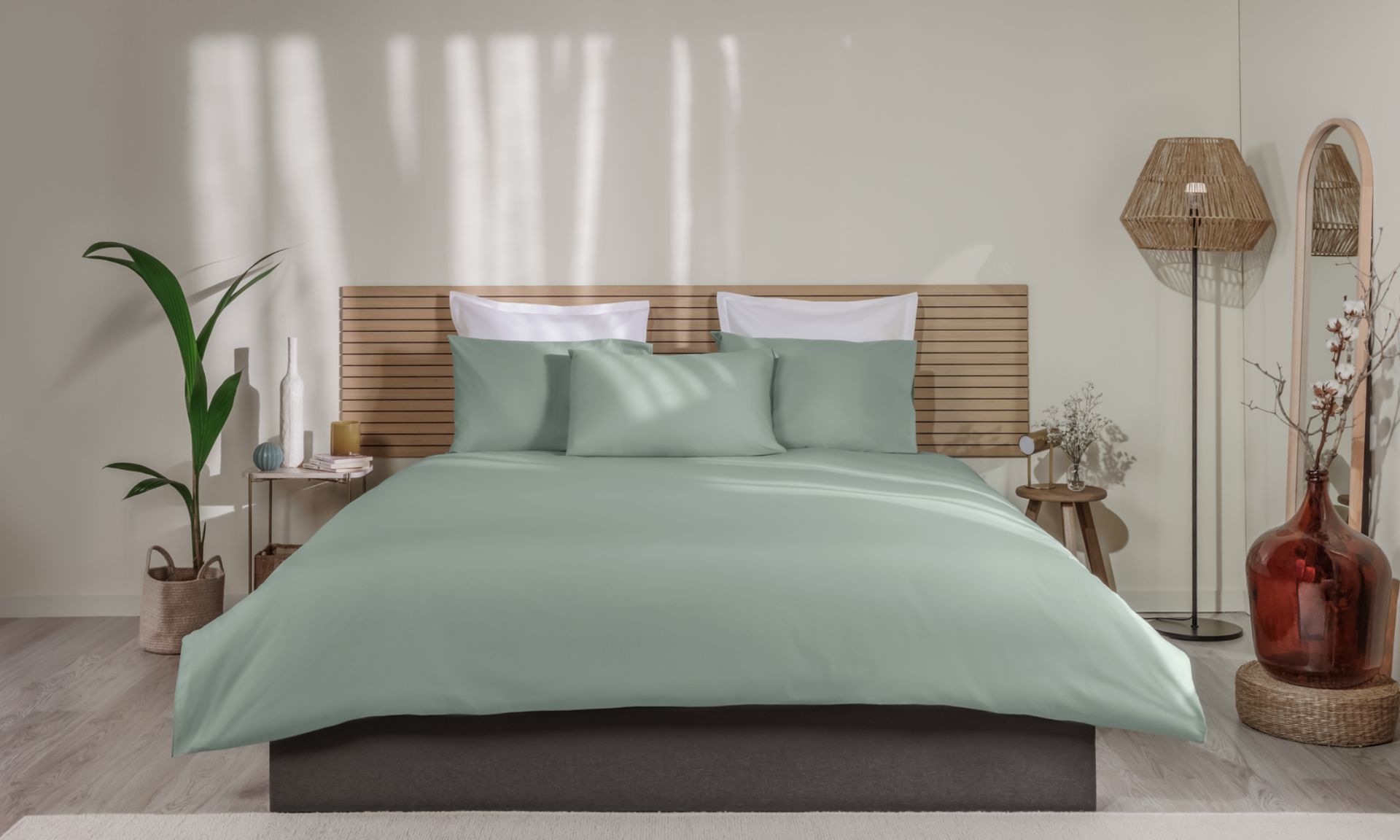 Letto ordinato con biancheria verde, testiera in legno e decorazioni su entrambi i lati.