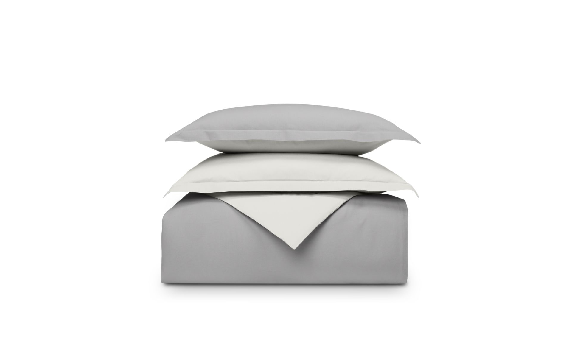 Set di biancheria piegato grigio e bianco sfondo bianco, cuscino sopra il piumone.