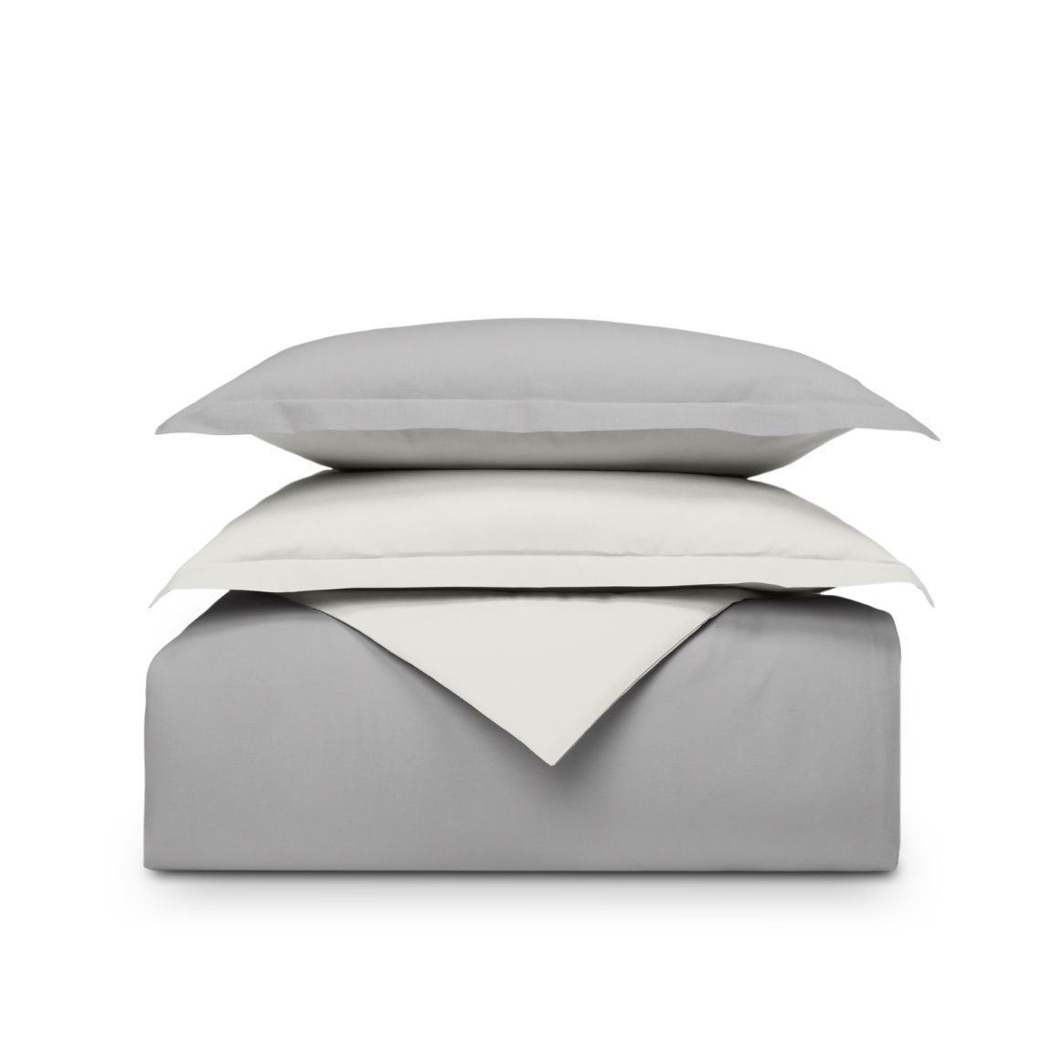 Set di biancheria piegato grigio e bianco sfondo bianco, cuscino sopra il piumone.