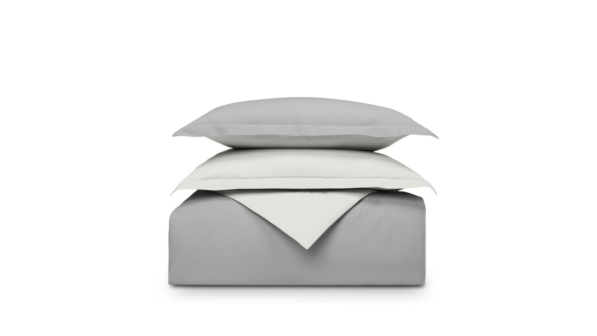 Set di biancheria piegato grigio e bianco sfondo bianco, cuscino sopra il piumone.