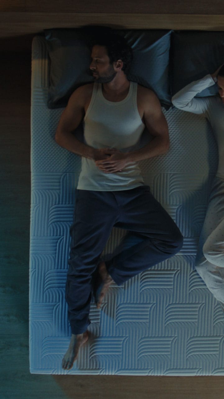 Man lying on textured Emma mattress showing breathable surface design.