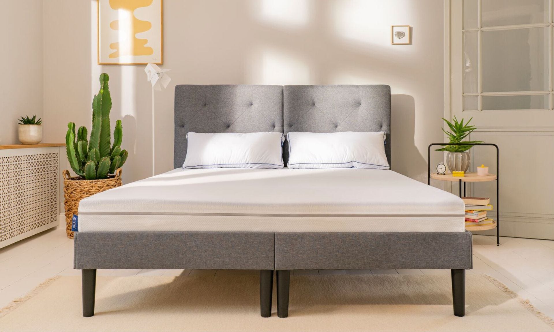 Colchón emma one en cama tapizada gris con 2 almohadas microfibra blancas